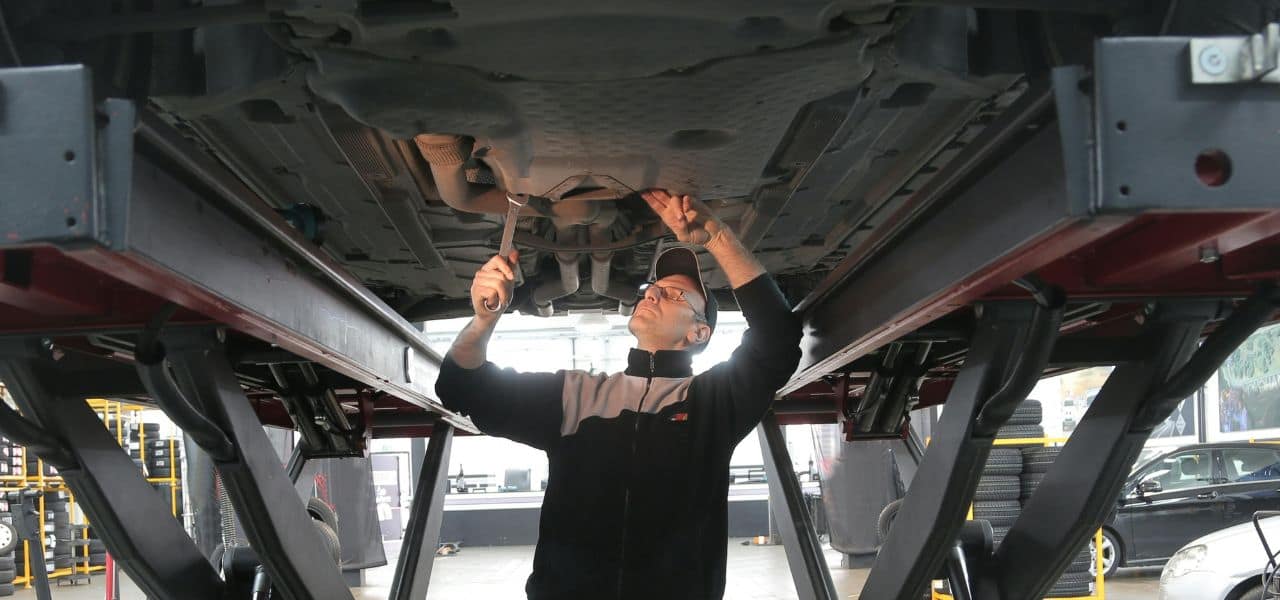 Voiture avec fuite de liquide de refroidissement visible sous le radiateur, conseils pour détecter et réparer efficacement les fuites de liquide moteur